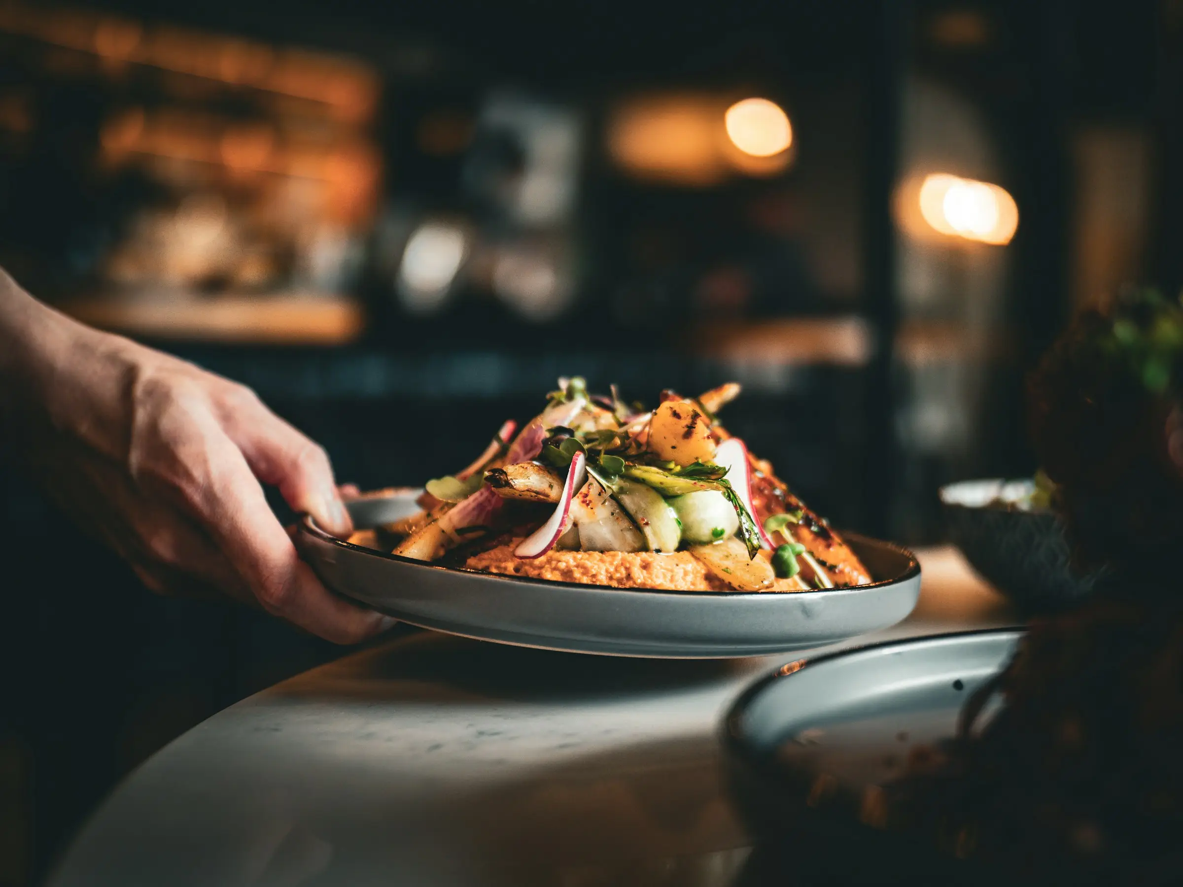 Servers carrying plates across a busy dining room